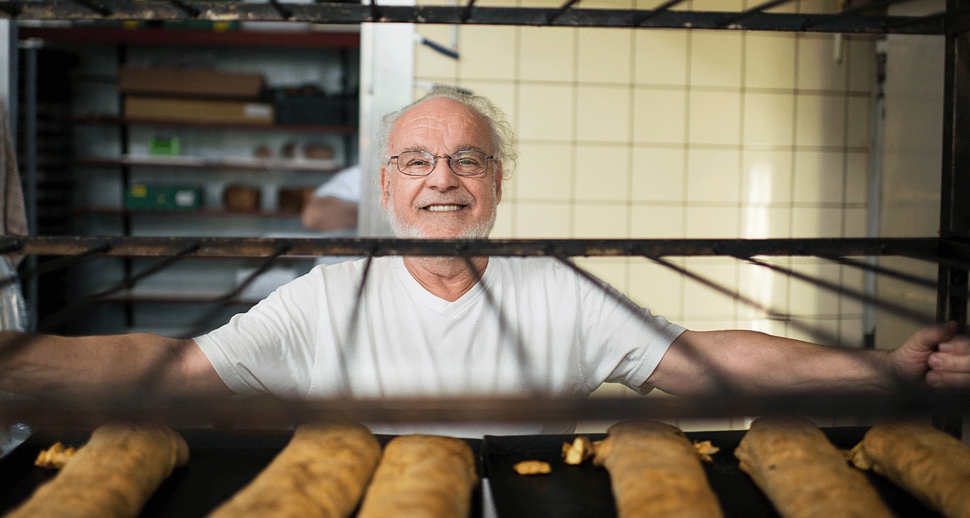 Een bakker staat achter een rek met versgebakken brood
